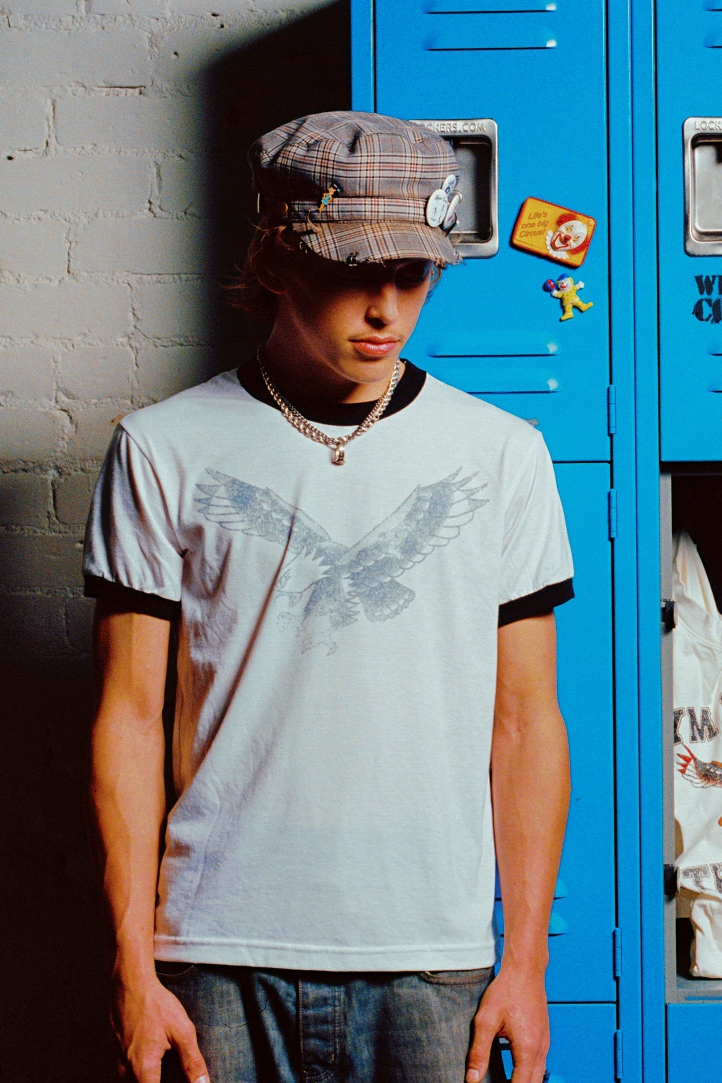 Person standing in front of blue lockers with graffiti on a wall